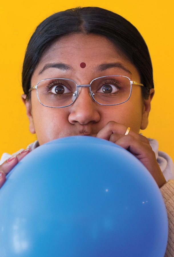 Indian women blowing up blue balloon