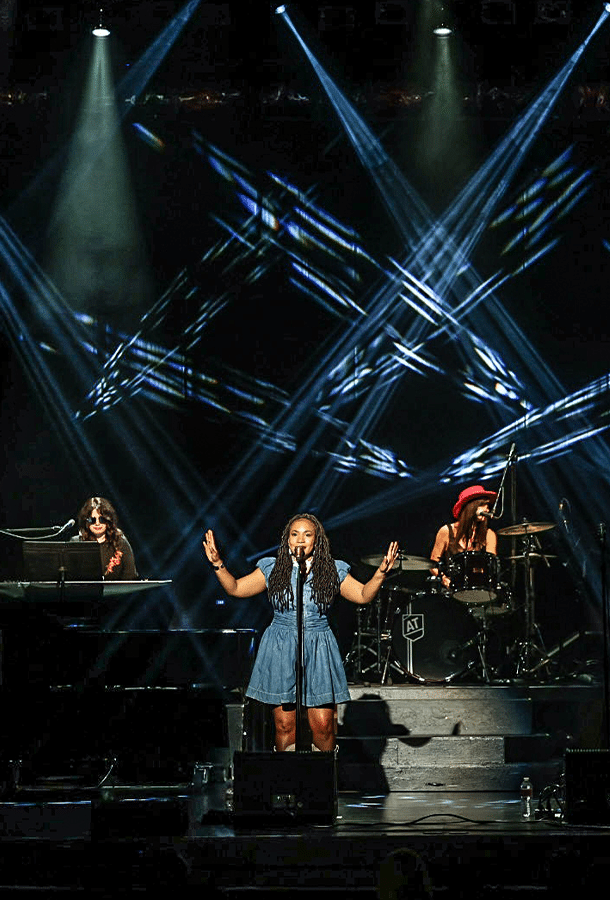 women sings in spot light with band behind her