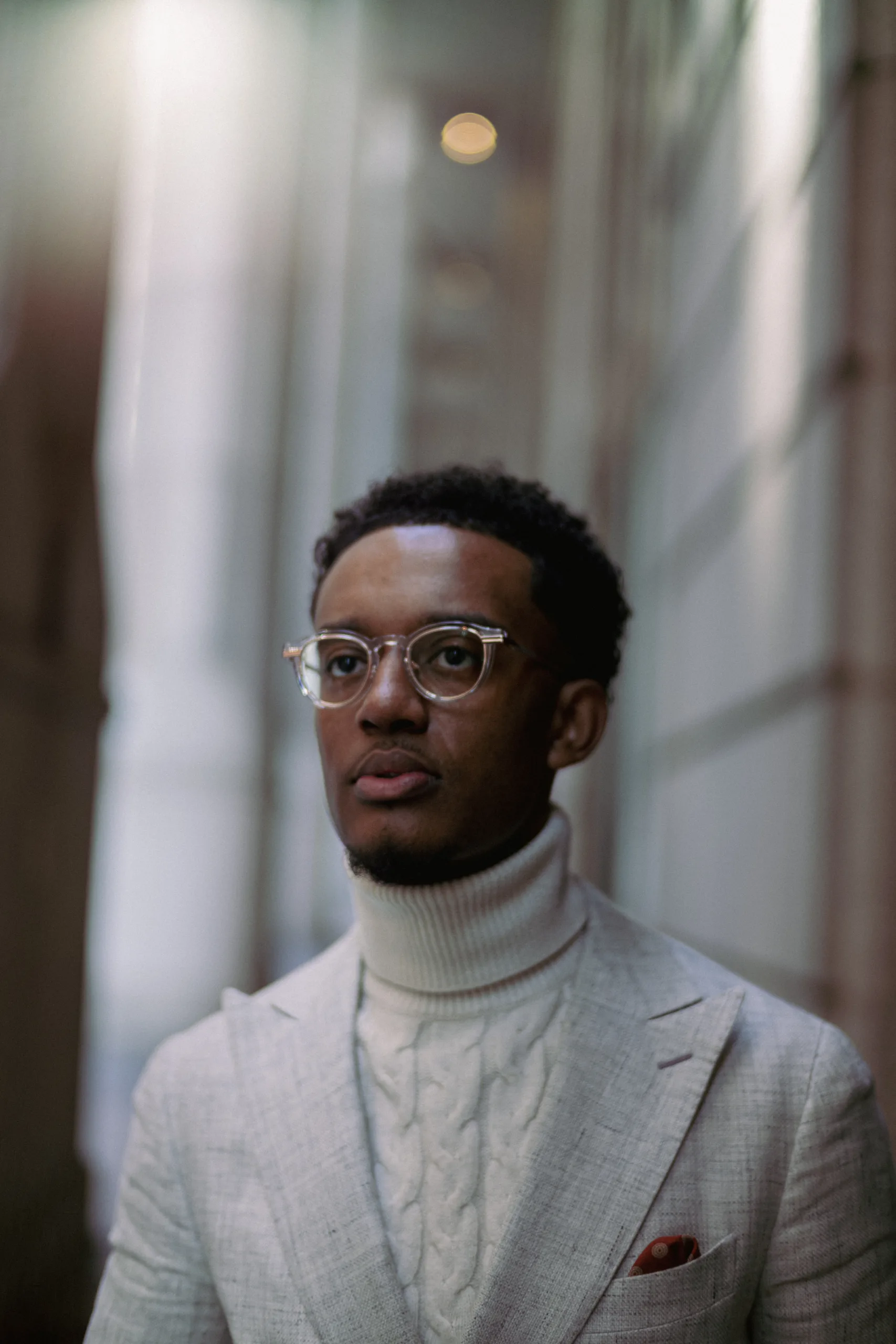 Luther S. Allison headshot wearing clear classes and white turtleneck sweater with blazer.