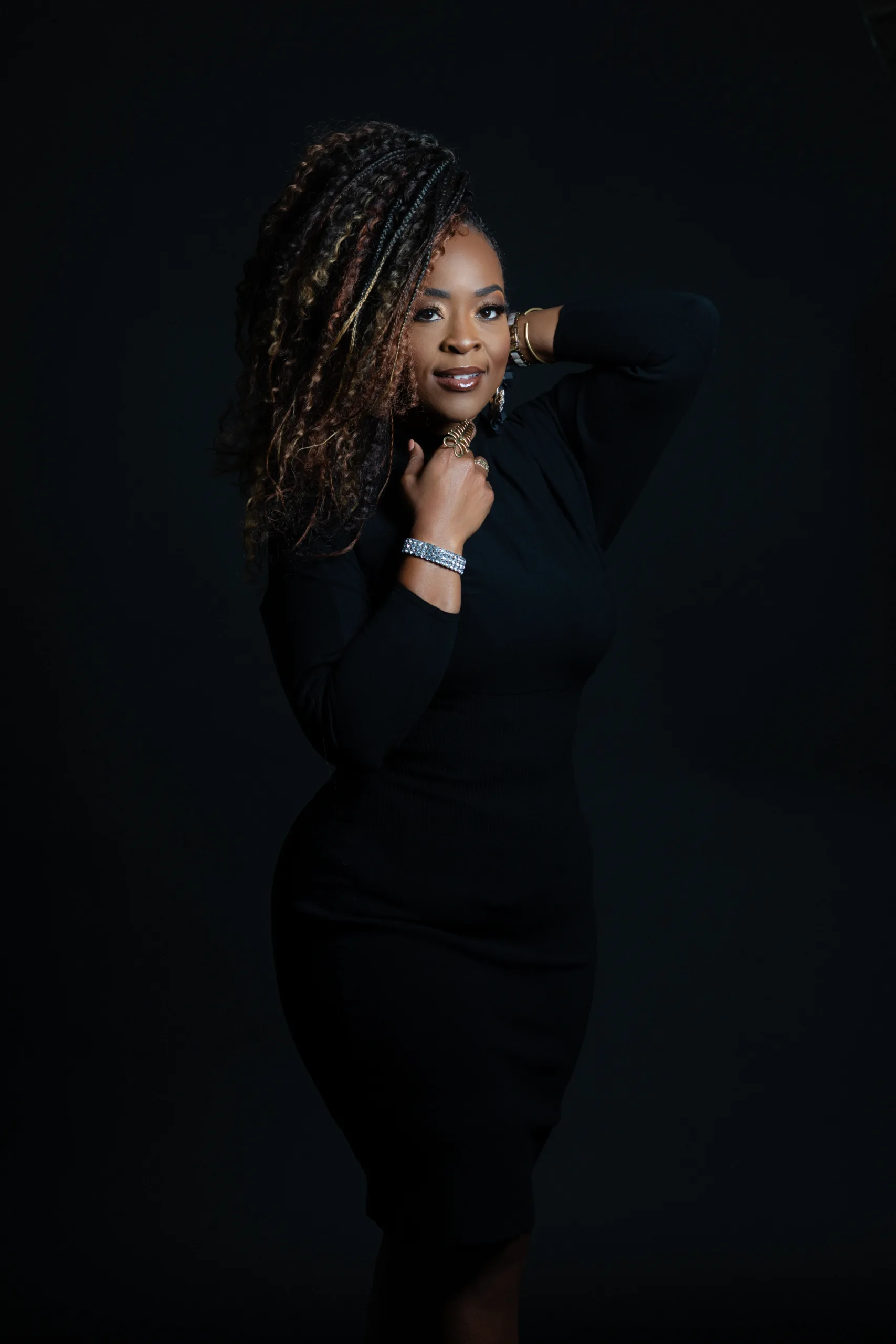 Quiana Lynell posing wearing black dress against dark background