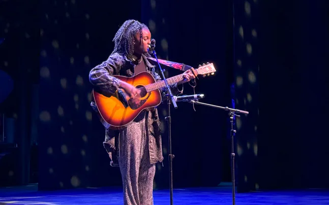 student playing guitar on stage.