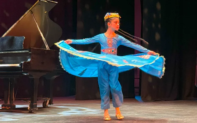 student in blue dress twirling