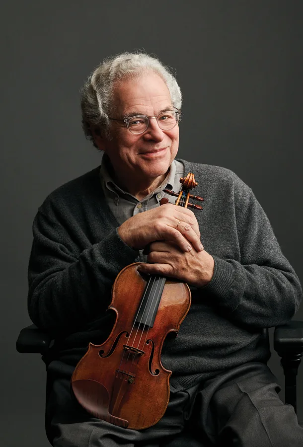 Itzhak Perlman headshot sitting down holding violin and smiling.